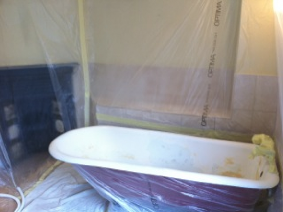 A bathroom showing preparation work for bath resurfacing. So masking sheets along the bath.